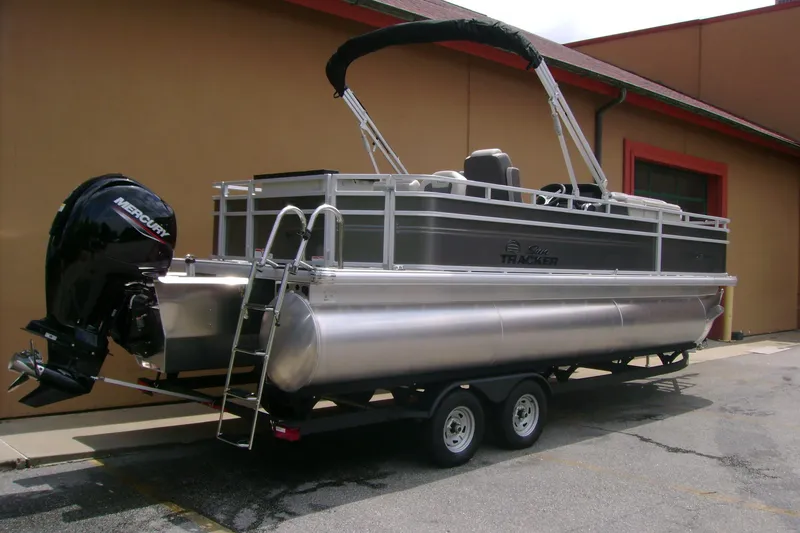 Slide: The Image of 2026 Sun Tracker Fishin' Barge 22 XP3 pontoon boat on trailer, parked outdoors. - 2