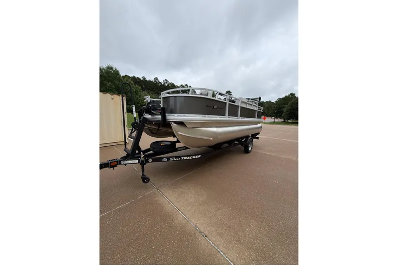 The Image of 2026 Sun Tracker Bass Buggy 18 DLX pontoon boat on trailer, parked outdoors. - 0