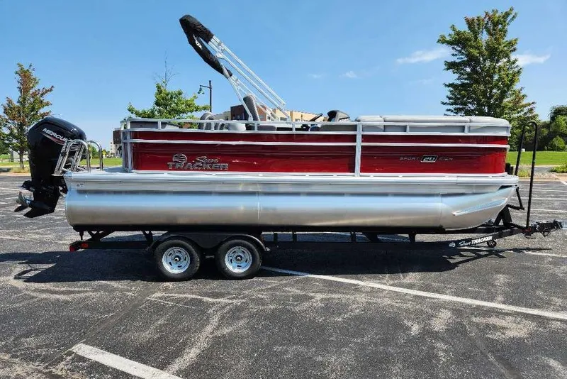 The Image of 2026 Sun Tracker SportFish 20 DLX pontoon boat on trailer in parking lot. - 0