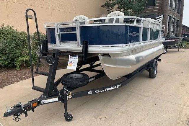 The Image of 2026 Sun Tracker Bass Buggy 18 DLX pontoon boat on trailer, parked outdoors. - 0