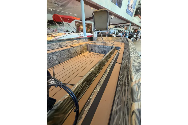 Slide: The Image of 2026 Tracker Grizzly 1756 T Marsh boat interior with camouflage design in showroom. - 2