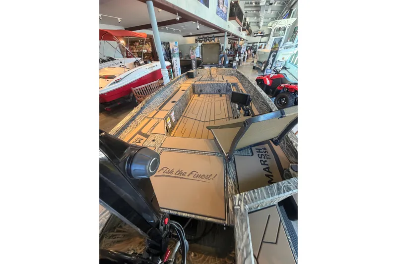 Slide: The Image of 2026 Tracker Grizzly 1756 T Marsh boat displayed in showroom, featuring spacious deck and storage. - 3