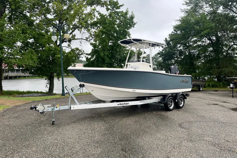 Slide: The Image of 2026 Mako 214 Center Console boat on trailer, parked near a scenic lake. - 1