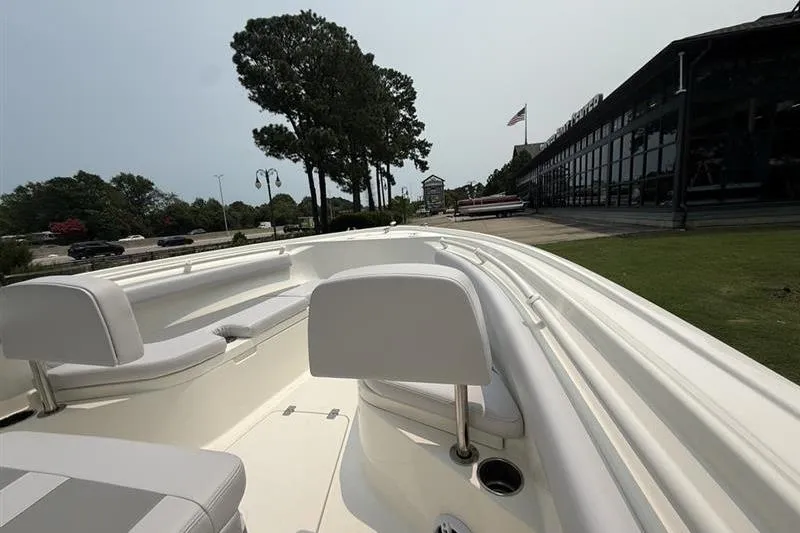 Slide: The Image of 2026 Mako 214 Center Console boat with white seating, parked near a building and trees. - 16