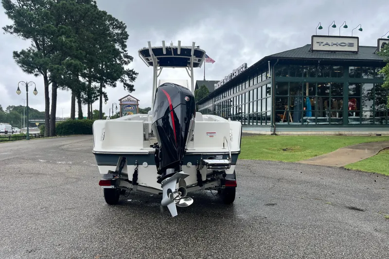 Slide: The Image of 2026 Mako 214 Center Console boat with outboard motor, parked near a showroom. - 3