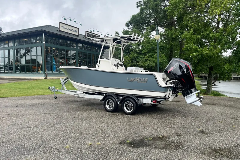 Slide: The Image of 2026 Mako 214 Center Console boat on trailer near dealership, surrounded by trees. - 2