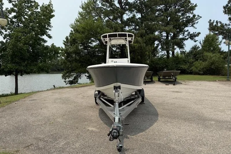 Slide: The Image of 2026 Mako 214 Center Console boat on trailer, parked near a lake with trees. - 3