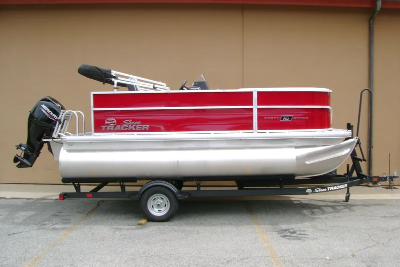 The Image of 2026 Sun Tracker Party Barge 16 DLX pontoon boat on trailer, red and silver design. - 0