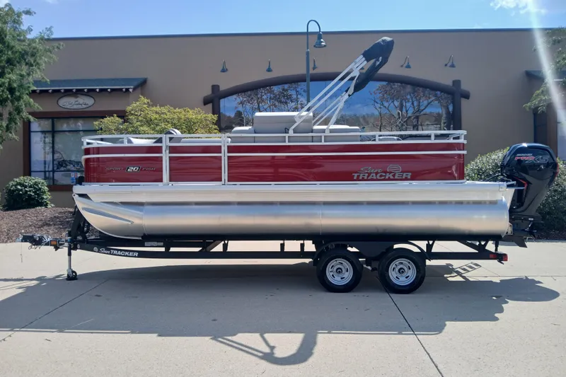The Image of 2026 Sun Tracker SportFish 20 DLX pontoon boat on trailer, parked outdoors. - 0