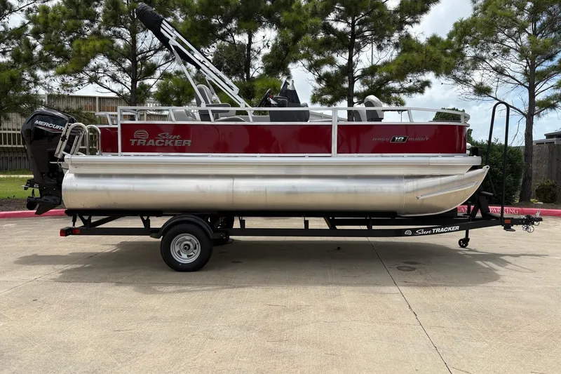 Slide: The Image of 2026 Sun Tracker Bass Buggy 18 DLX pontoon boat on trailer, parked outdoors. - 3