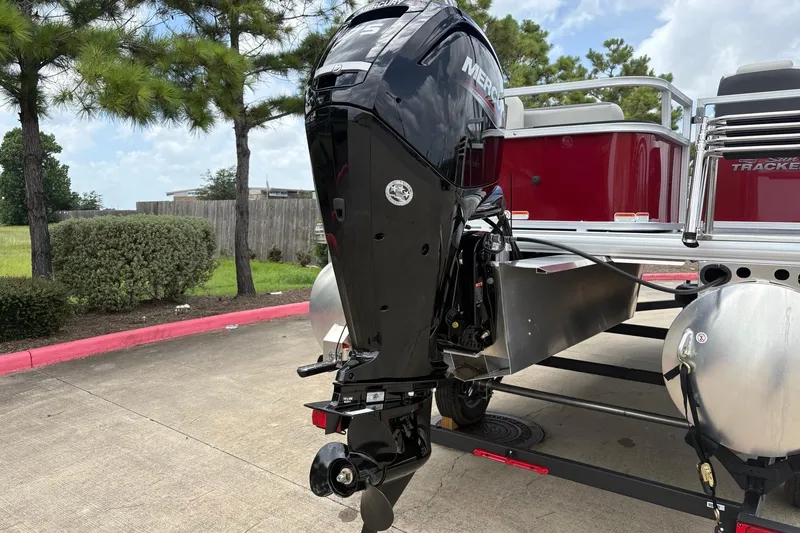 Slide: The Image of 2026 Sun Tracker Bass Buggy 18 DLX with Mercury outboard motor in a parking area. - 8