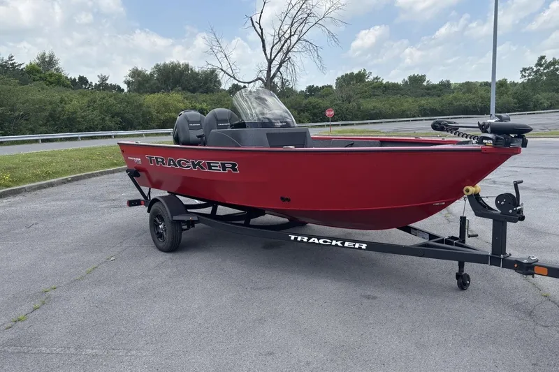 The Image of Red 2026 Tracker Pro Guide V-16 SC boat on trailer in parking lot. - 0