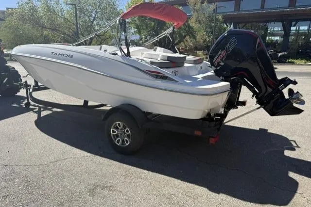 Slide: The Image of 2026 Tahoe T18 boat on trailer with outboard motor, parked outdoors. - 2
