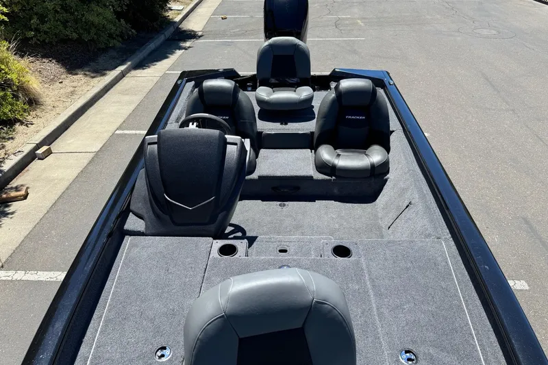 Slide: The Image of 2026 Tracker Pro Team 190 boat interior with seating and steering wheel, parked on pavement. - 9