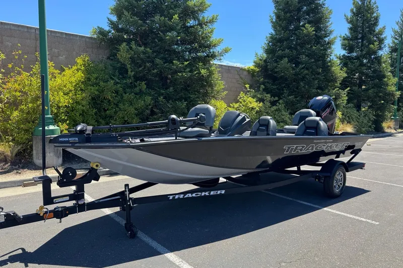 Slide: The Image of 2026 Tracker Pro Team 190 boat on trailer in parking lot, surrounded by trees. - 4