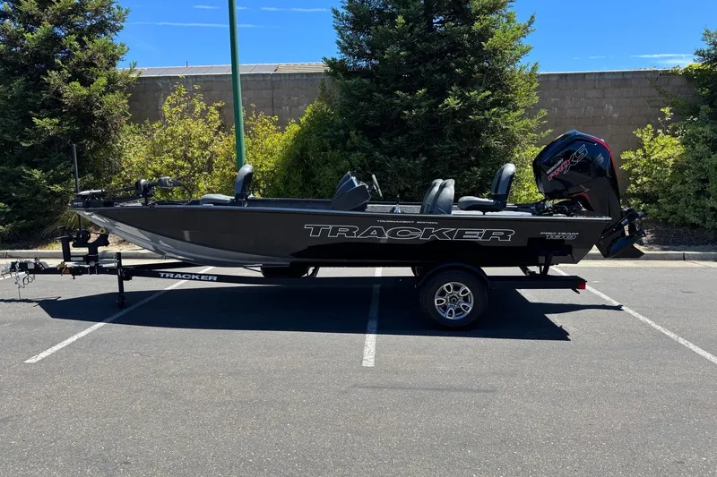 The Image of 2026 Tracker Pro Team 190 boat on trailer in parking lot, surrounded by trees. - 0