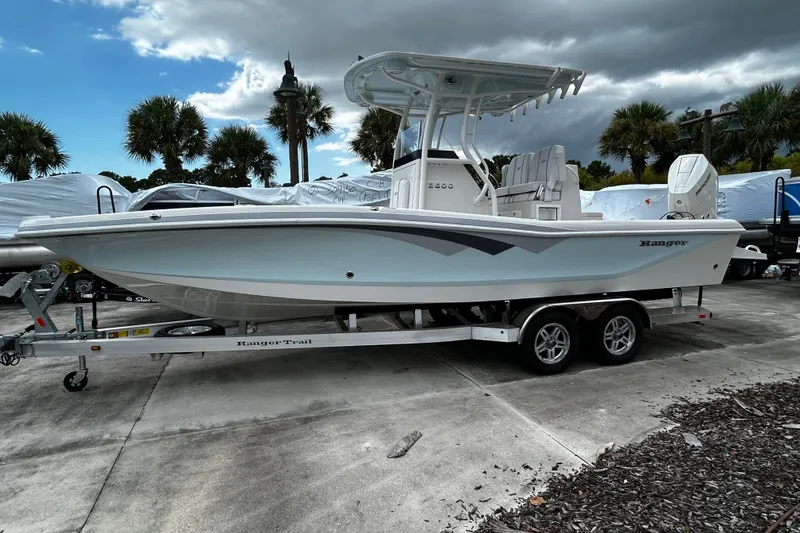 The Image of 2025 Ranger 2600 Bay boat on trailer, parked outdoors with palm trees in background. - 0