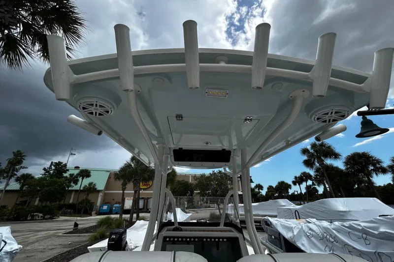 Slide: The Image of 2025 Ranger 2600 Bay boat with T-top and rod holders, under cloudy sky. - 10
