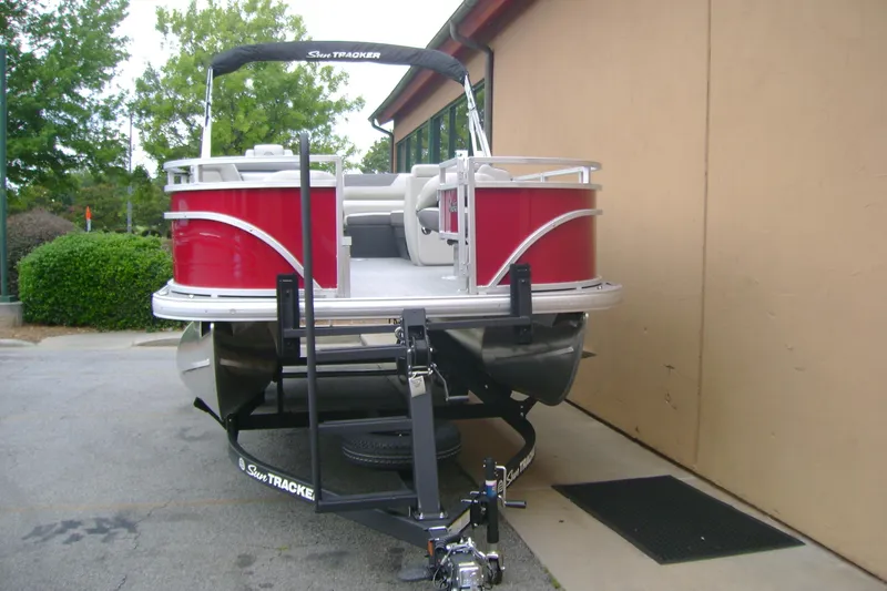 Slide: The Image of 2026 Sun Tracker Fishin' Barge 22 DLX pontoon boat on trailer, parked outdoors. - 3