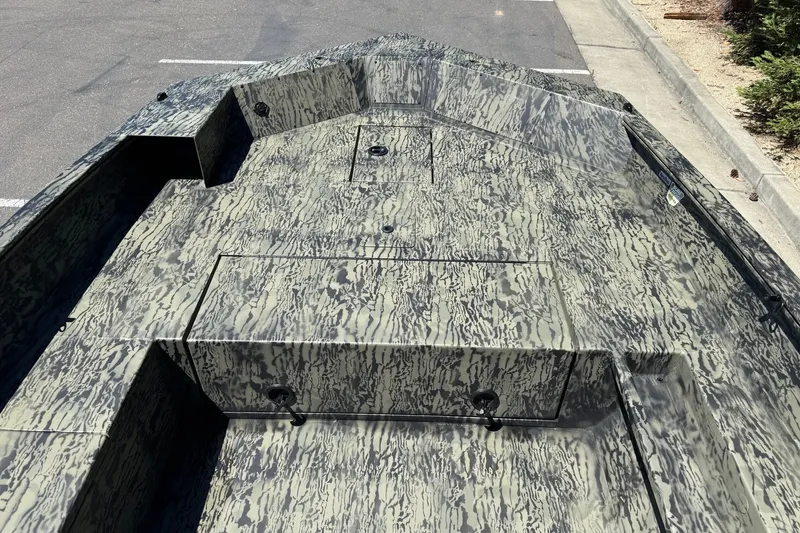 Slide: The Image of 2026 Tracker Grizzly 1756 T Marsh boat with camouflage pattern in a parking lot. - 10