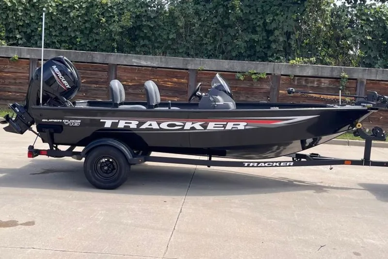 The Image of 2026 Tracker Super Guide V-16 SC fishing boat on trailer, parked outdoors. - 0