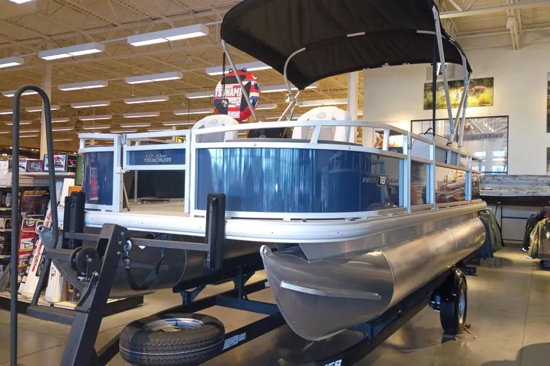 The Image of 2026 Sun Tracker Bass Buggy 18 DLX pontoon boat displayed indoors on a trailer. - 0