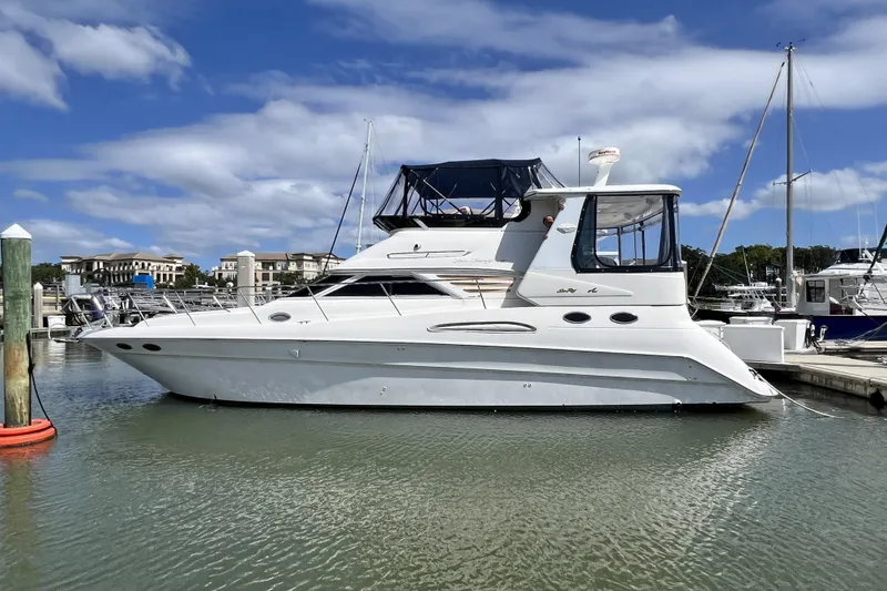 The Image of 1999 Sea Ray 420 Aft Cabin yacht docked in a marina under a blue sky. - 0