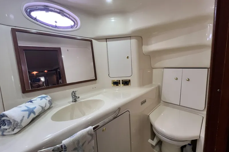Slide: The Image of 1999 Sea Ray 420 Aft Cabin bathroom with sink, mirror, and storage cabinets. - 18