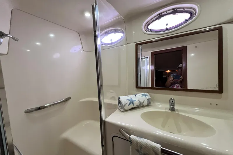 Slide: The Image of 1999 Sea Ray 420 Aft Cabin bathroom with mirror, sink, and porthole window. - 19