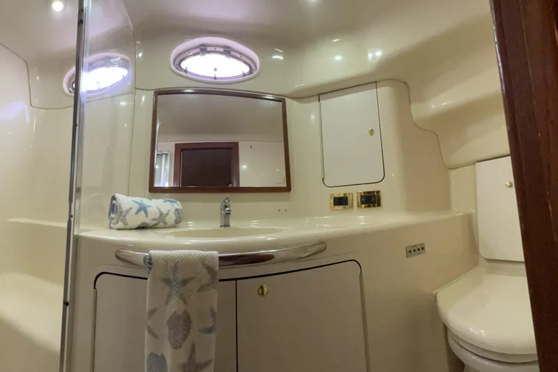 Slide: The Image of 1999 Sea Ray 420 Aft Cabin bathroom with mirror, sink, and nautical-themed towels. - 20
