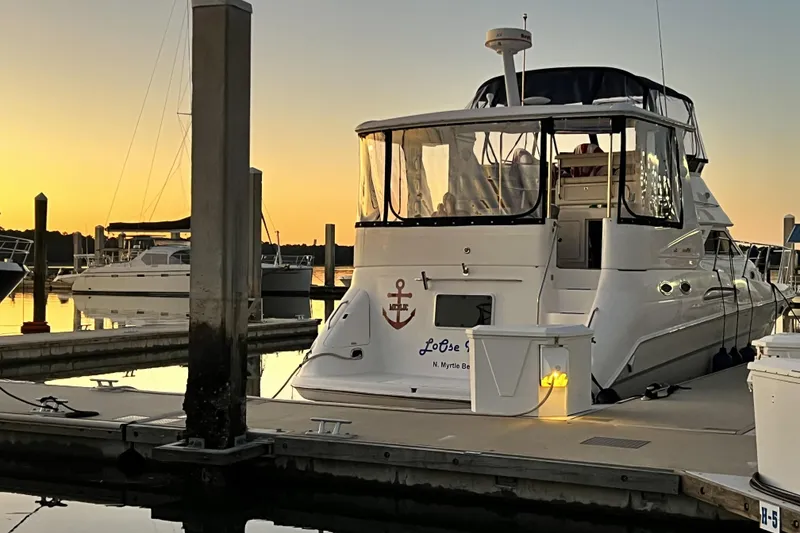Slide: The Image of 1999 Sea Ray 420 Aft Cabin yacht docked at sunset, reflecting on calm water. - 4