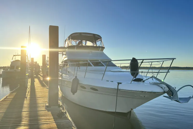 Slide: The Image of 1999 Sea Ray 420 Aft Cabin yacht docked at sunrise, reflecting on calm water. - 6