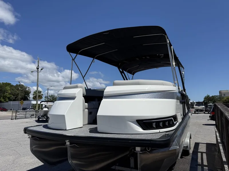 Slide: The Image of A modern pontoon boat with a black sunshade and sleek white seating, parked on a lot. - 3