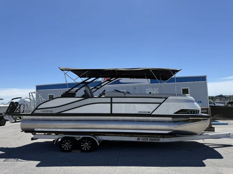 Slide: The Image of A 2027 Harris Grand Mariner 250 on a trailer in front of a building. - 0