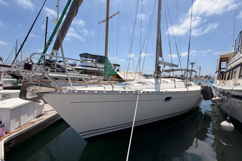 The Image of 1999 Jeanneau Sun Odyssey 45.2 sailboat docked at marina under blue sky. - 0