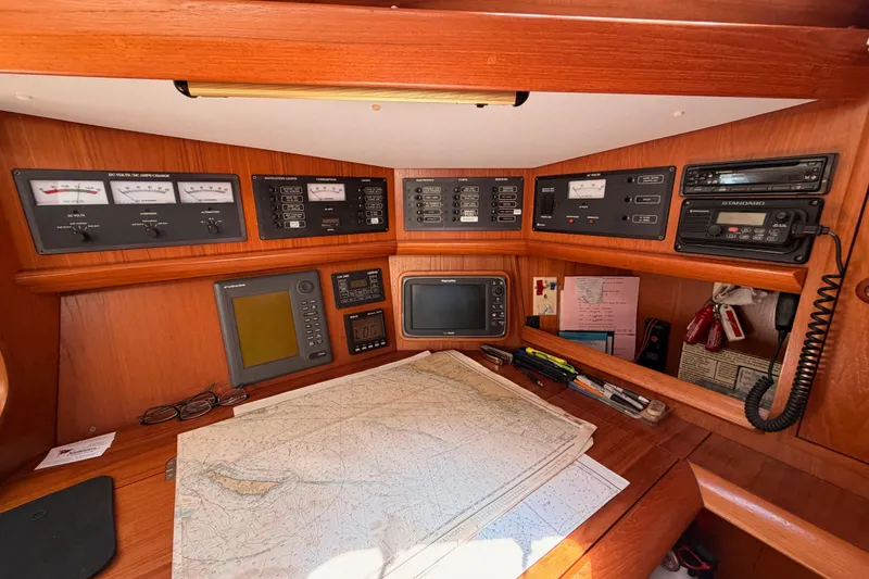 Slide: The Image of Navigation station of 1999 Jeanneau Sun Odyssey 45.2 with control panels and nautical charts. - 41