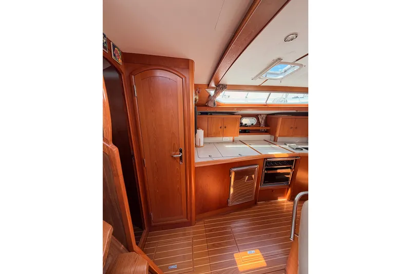 Slide: The Image of Interior of 1999 Jeanneau Sun Odyssey 45.2 yacht, featuring a wooden kitchen and cabinetry. - 49