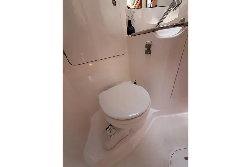 Slide: The Image of Bathroom interior of 1999 Jeanneau Sun Odyssey 45.2 yacht, featuring a compact toilet. - 51