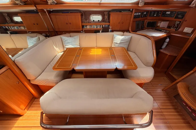 Slide: The Image of Interior of 1999 Jeanneau Sun Odyssey 45.2 yacht with wooden dining area and cushioned seating. - 57