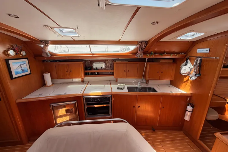 Slide: The Image of Interior of 1999 Jeanneau Sun Odyssey 45.2 yacht, featuring a well-equipped wooden kitchen. - 59