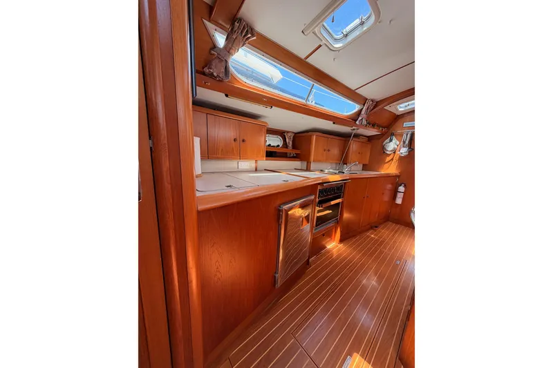 Slide: The Image of Interior of 1999 Jeanneau Sun Odyssey 45.2 yacht, featuring a wooden galley and modern amenities. - 60