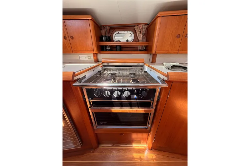 Slide: The Image of Galley kitchen in 1999 Jeanneau Sun Odyssey 45.2 sailboat with wooden cabinetry and stove. - 62
