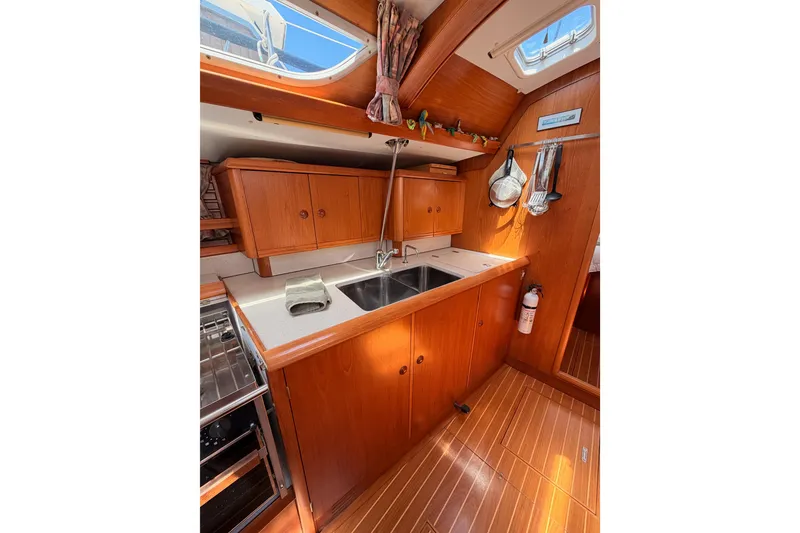 Slide: The Image of Interior of 1999 Jeanneau Sun Odyssey 45.2 yacht kitchen with wooden cabinetry and dual sink. - 63