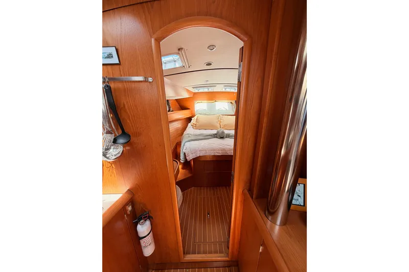 Slide: The Image of Interior of 1999 Jeanneau Sun Odyssey 45.2 yacht, featuring cozy wooden cabin and bed. - 65