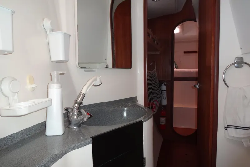 Slide: The Image of Bathroom interior of 1996 Lagoon 35 CCC yacht, featuring sink, mirror, and wooden cabinetry. - 127