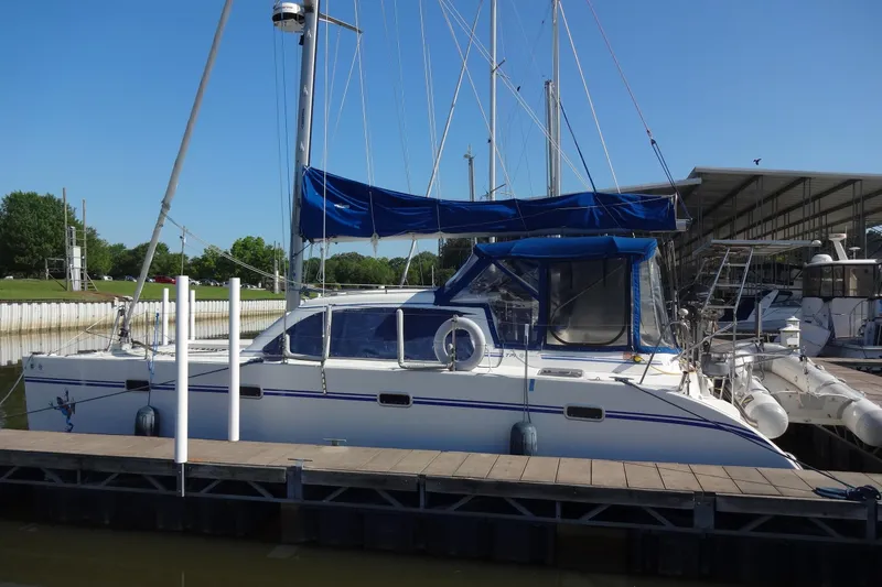 Slide: The Image of 1996 Lagoon 35 CCC catamaran docked at marina, featuring blue sail covers and clear skies. - 17