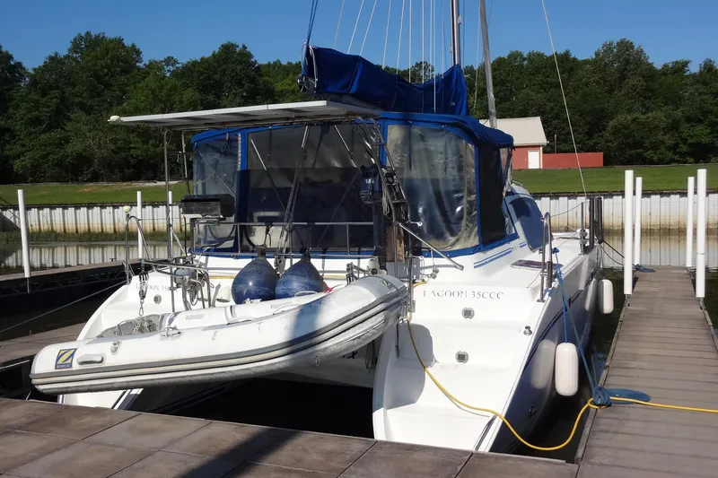 Slide: The Image of 1996 Lagoon 35 CCC catamaran docked, featuring blue canopy and inflatable dinghy. - 21
