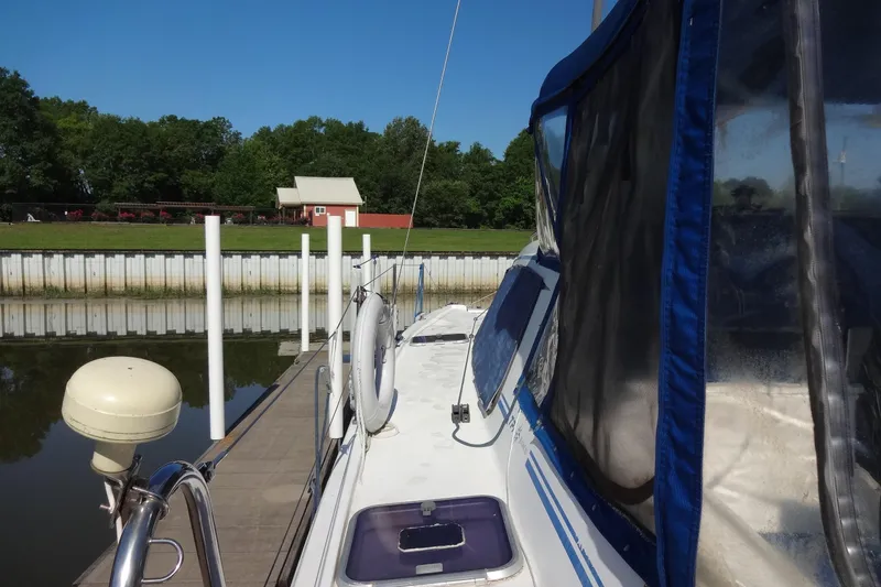 Slide: The Image of 1996 Lagoon 35 CCC sailboat docked by a serene waterfront with lush greenery. - 52