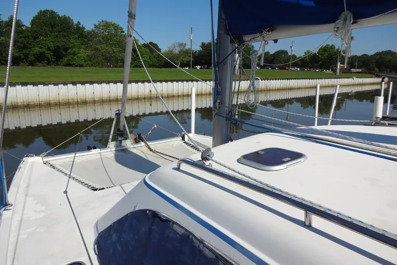 Slide: The Image of 1996 Lagoon 35 CCC catamaran docked by a calm river with lush greenery. - 54