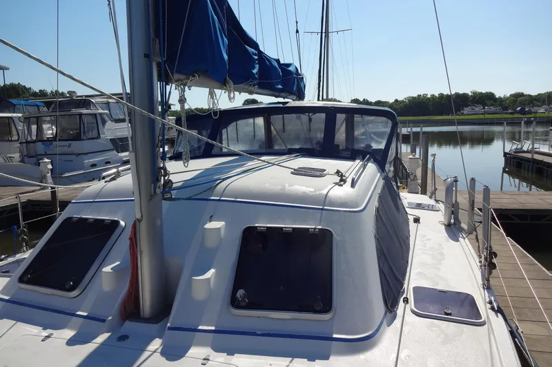 Slide: The Image of 1996 Lagoon 35 CCC sailboat docked at a marina, featuring a sleek design and blue sail cover. - 55